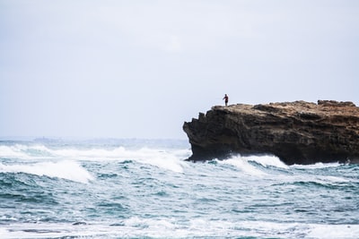 男人站在岩石看着大海
